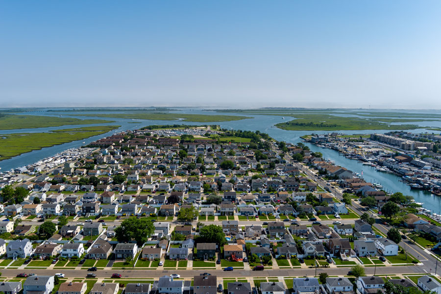 An aerial view of Freeport shows residential neighborhoods surrounded by canals, marinas, tidal waterways, and expansive salt marshes along the South Shore of Long Island. Freeport is an incorporated village within the Town of Hempstead, illustrating how Long Island's towns can contain numerous villages, hamlets, waterfront districts, and distinct local communities.