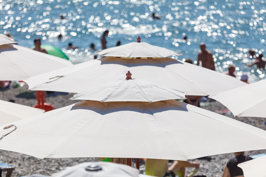 Beach umbrellas line the shoreline as visitors enjoy a busy summer day on Long Island's Atlantic coast. While popular beaches can become crowded during weekends and holidays, visiting less-traveled beaches or arriving early on weekdays can provide a quieter and more relaxing beach experience.