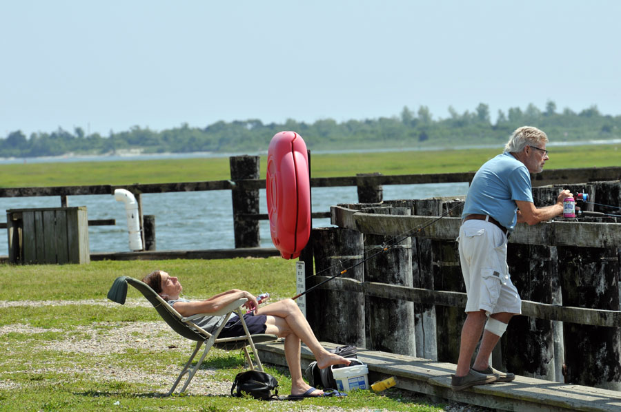 Anglers enjoy a relaxing day of fishing from a public pier at the Nautical Mile in Freeport, one of many waterfront locations where residents and visitors can cast a line without needing a boat. Long Island's public fishing piers offer convenient access to productive saltwater fishing throughout much of the year. File photo: Arnett Murry, licensed.