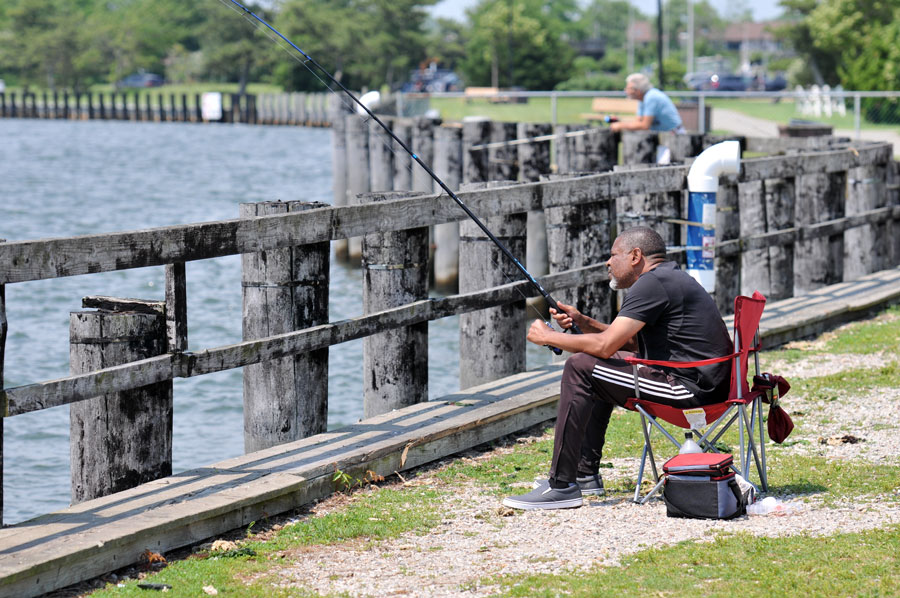 An angler fishes from the public pier at the Nautical Mile in Freeport, one of Long Island's popular waterfront destinations for recreational fishing. From public piers and marinas to beaches, bays, lakes, and the open ocean, the island offers abundant fishing opportunities for anglers of all experience levels throughout the year. File photo: Arnett Murry, licensed.