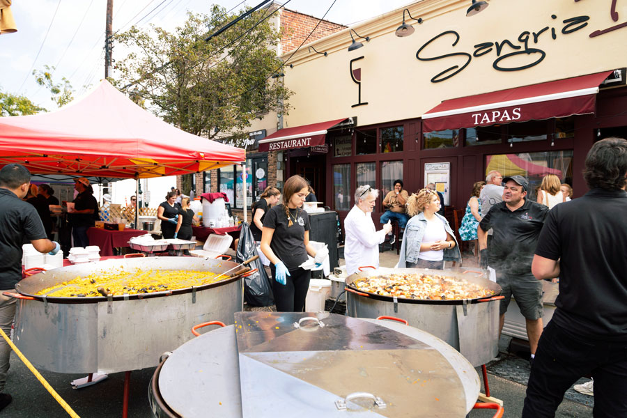 A lively street food festival brings visitors together outside a popular Long Island restaurant, where oversized paella pans, local flavors, and outdoor dining showcase the island's diverse culinary scene and vibrant community atmosphere. File photo: Francesco Joseph, licensed.