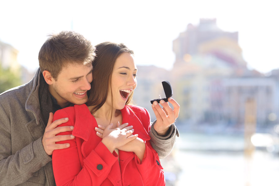 A young couple celebrates a surprise marriage proposal as the newly engaged woman admires her engagement ring with excitement. The joyful moment captures the romance and emotion of one of life's most memorable occasions, making it an ideal image for a guide to the best places to get engaged on Long Island.