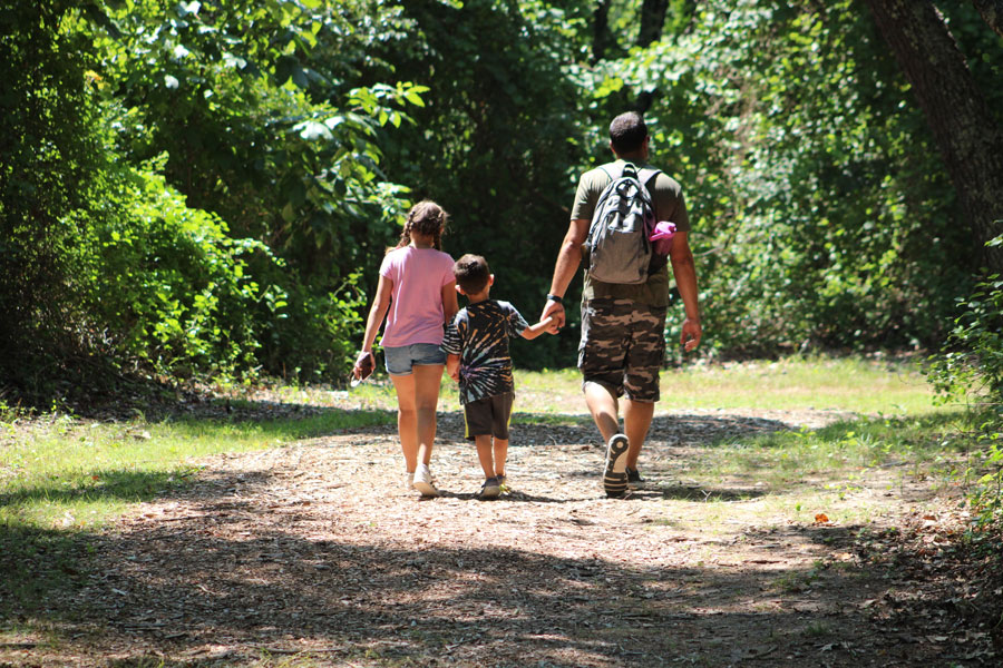 A family enjoys a peaceful hike along a wooded trail in Mashomack Preserve on Shelter Island. With miles of scenic trails winding through forests, wetlands, and tidal creeks, Mashomack is one of Long Island's premier destinations for hiking, birdwatching, wildlife viewing, and experiencing the island's natural beauty. 