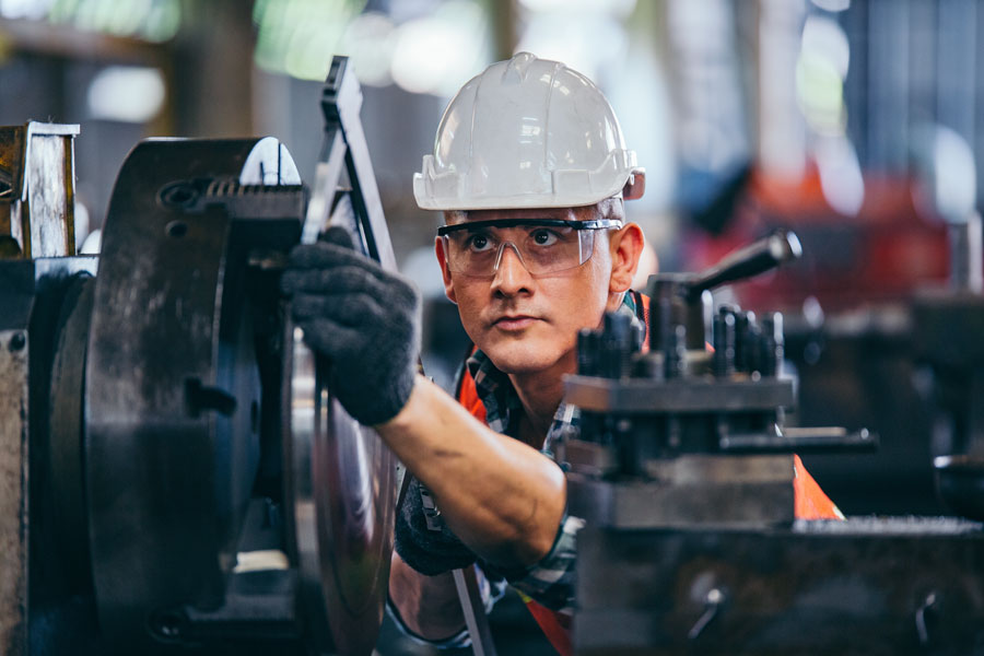 A skilled manufacturing worker operates industrial machinery, representing one of the many industries that help drive Long Island's economy. While healthcare, education, and research now employ the largest share of the workforce, manufacturing, engineering, aerospace, and advanced technology continue to play important roles across the region. File photo: Winnievinzence, licensed.