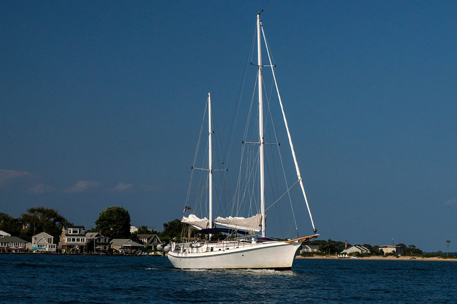 A sailboat glides across the calm waters of Greenport Harbor on Long Island's North Fork. With its scenic waterfront, protected harbor, and direct access to the Peconic Bays and Long Island Sound, Greenport is one of the island's premier destinations for recreational sailing and boating.
