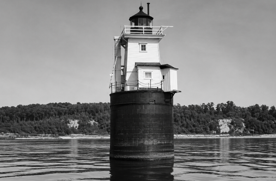 The Cold Spring Harbor Lighthouse stands on its stone caisson in this historic view, marking the entrance to Cold Spring Harbor on Long Island’s North Shore. The former navigational landmark guided vessels through the harbor before it was dismantled and removed.