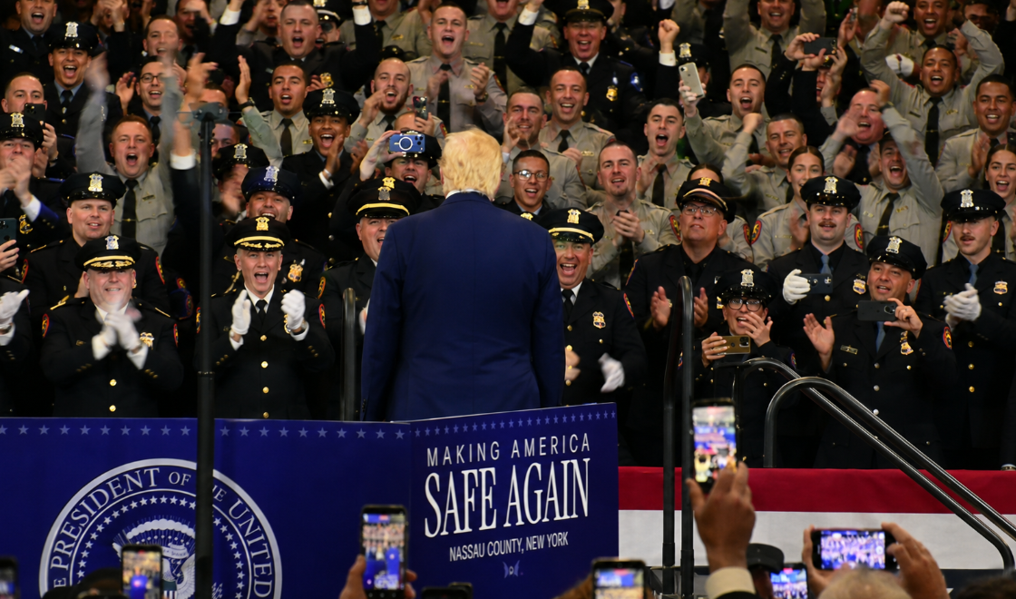 President Donald Trump is greeted by an enthusiastic crowd of uniformed law enforcement officers during his August 14, 2026, appearance at the Nassau County Police Academy in Uniondale, New York. Trump visited Long Island to deliver remarks focused on falling violent crime rates, policing and public safety.