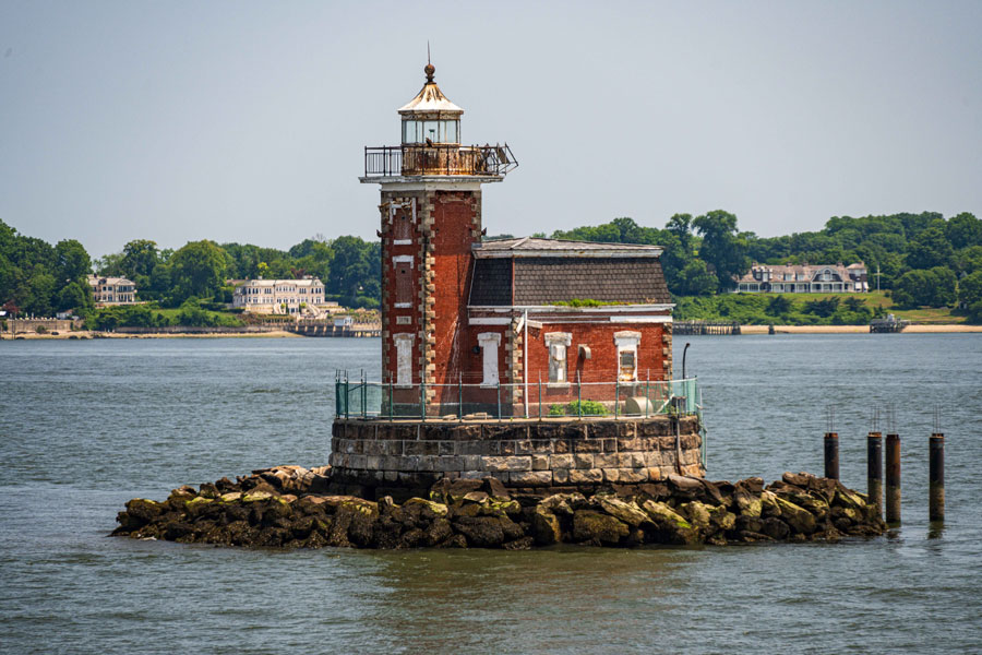 Stepping Stones Lighthouse stands on a rocky reef in Long Island Sound, approximately 1,600 yards offshore from Kings Point, Long Island. Built in 1876, the historic red-brick lighthouse remains an active navigational aid and can be viewed from surrounding waterfront areas or by boat.