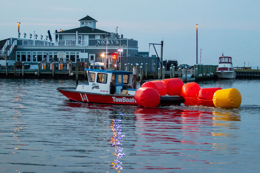 A TowBoatUS vessel moves through the calm waters of Bay Shore Marina, with Nicky’s on the Bay and docked boats in the background. The scene captures the relaxed waterfront atmosphere that makes Bay Shore a popular destination for marina dining, boating, and Great South Bay views.