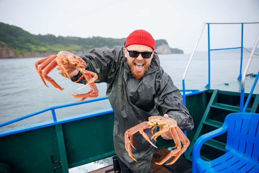 A recreational crabber proudly displays two freshly caught crabs aboard a fishing boat. Crabbing is a popular saltwater activity in coastal communities, including bays and shoreline access points throughout Long Island.