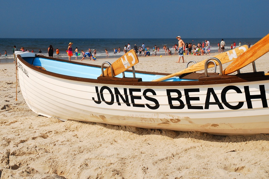 A lifeguard boat rests on the sand at Jones Beach State Park as visitors enjoy a busy summer day along Long Island's Atlantic coastline. Jones Beach is one of New York's most iconic public beaches, known for its wide sandy shoreline, swimming, boardwalk, and family-friendly recreation.