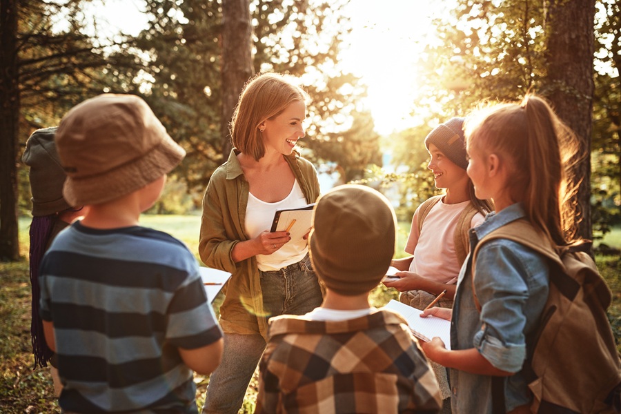 A summer camp counselor leads a group of children in an outdoor educational activity. Long Island summer camps offer programs ranging from nature exploration and sports to arts, science and traditional day-camp recreation. Families can compare locations and program types to find a camp that suits their children’s interests and needs.