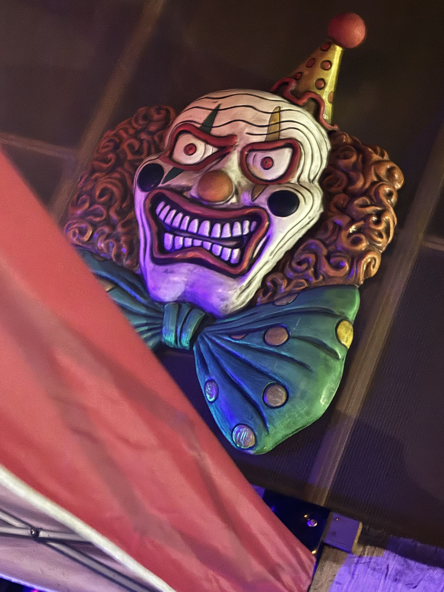 A menacing clown display inside Schmitt’s Farm Haunt in Melville during the 2024 Halloween season. Elaborate props, theatrical lighting and horror-themed scenery are part of the attraction’s annual haunted experience. Photo: LongIslandGuide.com, 2024.