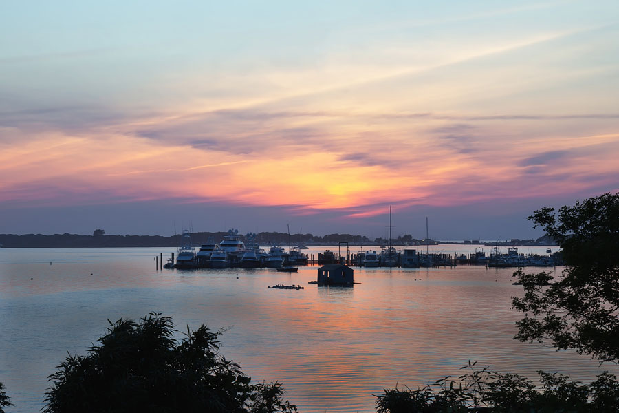 Lake Montauk at sunset, with boats and docks silhouetted against the colorful evening sky in Montauk, New York. The tidal lake, once a freshwater body known as the Great Lake, now serves as an important center for boating, fishing and maritime activity on Long Island’s East End. File photo: Galina Gutarin, licensed.