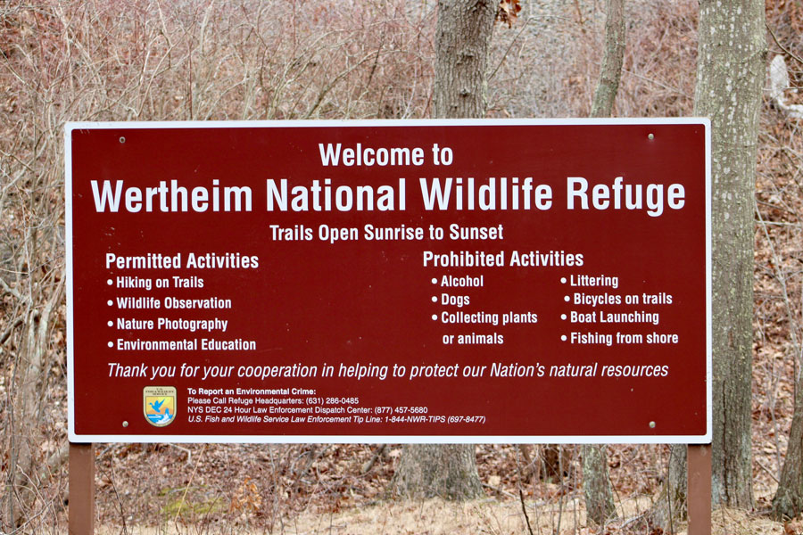 Wertheim National Wildlife Refuge entrance sign in Shirley, New York, lists permitted activities and visitor rules, including trail access from sunrise to sunset. The 2,550-acre refuge protects forests, wetlands and wildlife habitat along the Carmans River in Suffolk County.